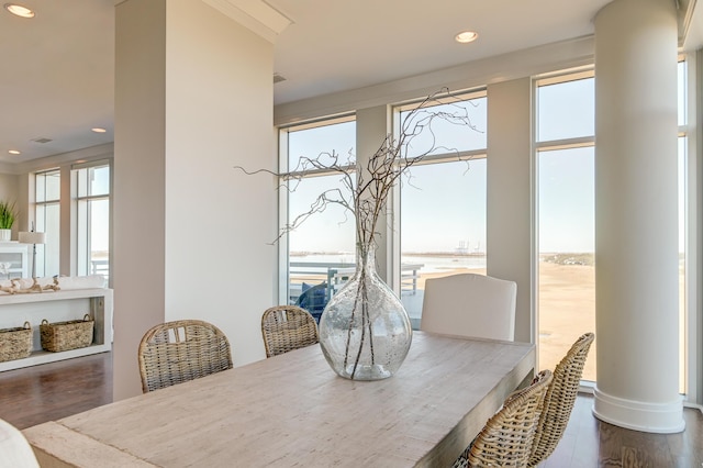 dining area with wood-type flooring, a water view, and ornate columns