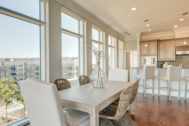 dining area with dark wood-type flooring, a baseboard heating unit, and ornamental molding