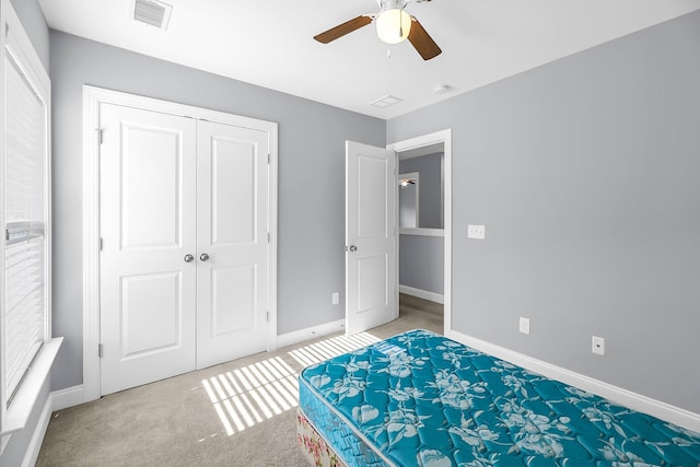 unfurnished bedroom with a closet, visible vents, a ceiling fan, light carpet, and baseboards