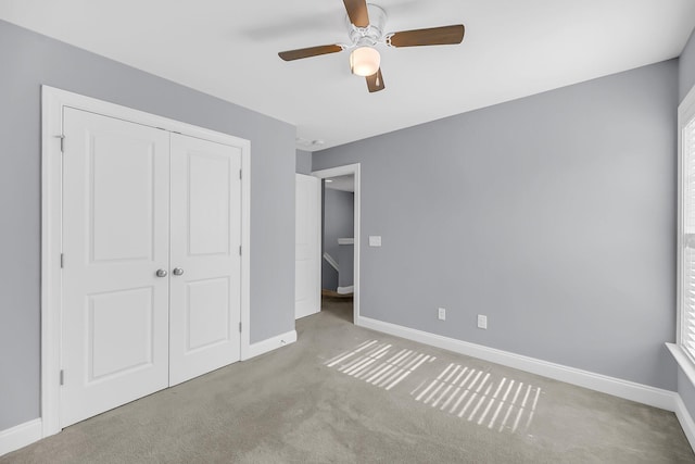 unfurnished bedroom featuring a closet, carpet, a ceiling fan, and baseboards