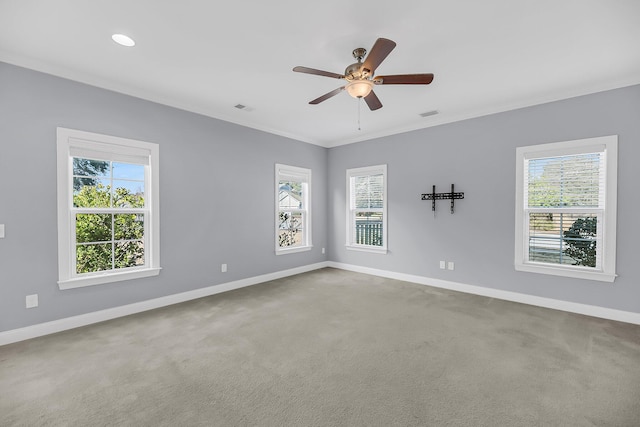 carpeted empty room featuring a ceiling fan, visible vents, crown molding, and baseboards