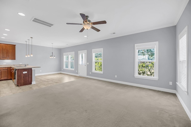 unfurnished living room with crown molding, visible vents, a sink, and light colored carpet