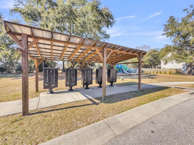 surrounding community with playground community, a lawn, and mail area