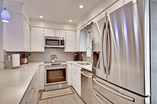 kitchen with white cabinets, hanging light fixtures, a sink, stainless steel appliances, and backsplash