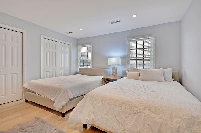 bedroom with recessed lighting, visible vents, multiple closets, and wood finished floors