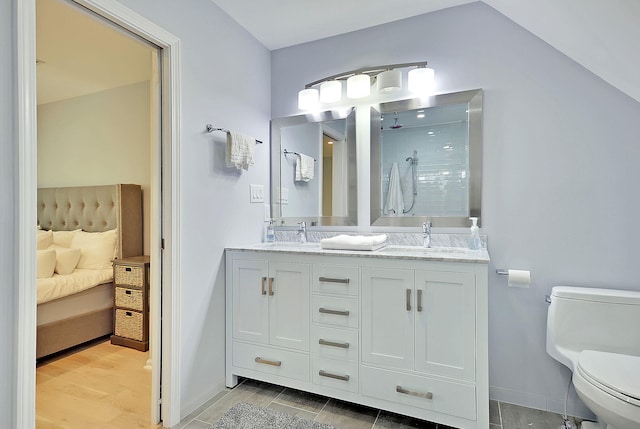 ensuite bathroom featuring toilet, ensuite bath, double vanity, and a sink