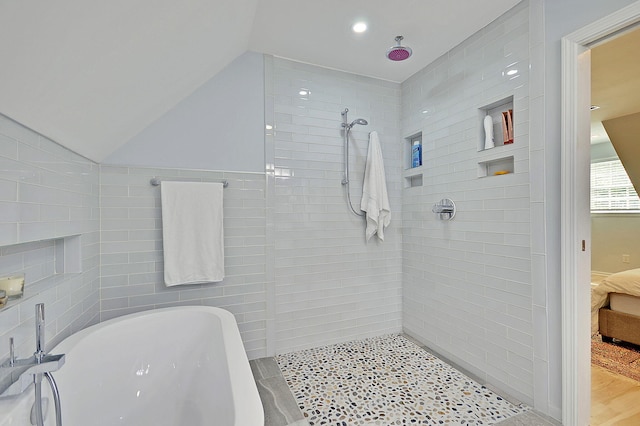 ensuite bathroom featuring ensuite bath, vaulted ceiling, tile walls, and tiled shower