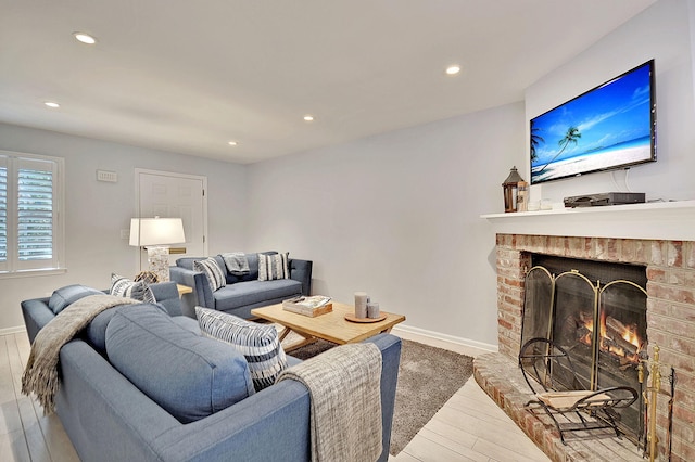 living area with light wood finished floors, a brick fireplace, recessed lighting, and baseboards