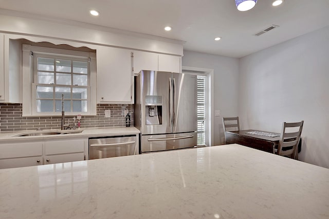 kitchen with appliances with stainless steel finishes, white cabinetry, a sink, and visible vents