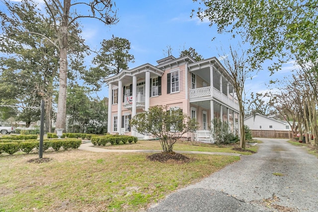 greek revival house featuring a balcony and a front yard