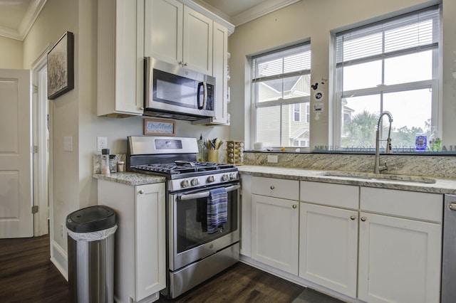 kitchen featuring crown molding, a sink, stainless steel appliances, white cabinetry, and dark wood-style floors