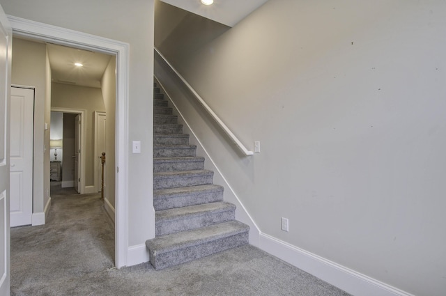 stairway with baseboards and carpet flooring