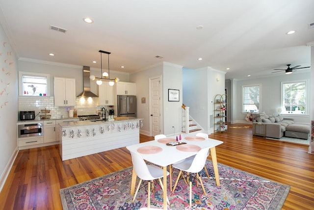 dining area featuring sink, hardwood / wood-style flooring, and ornamental molding