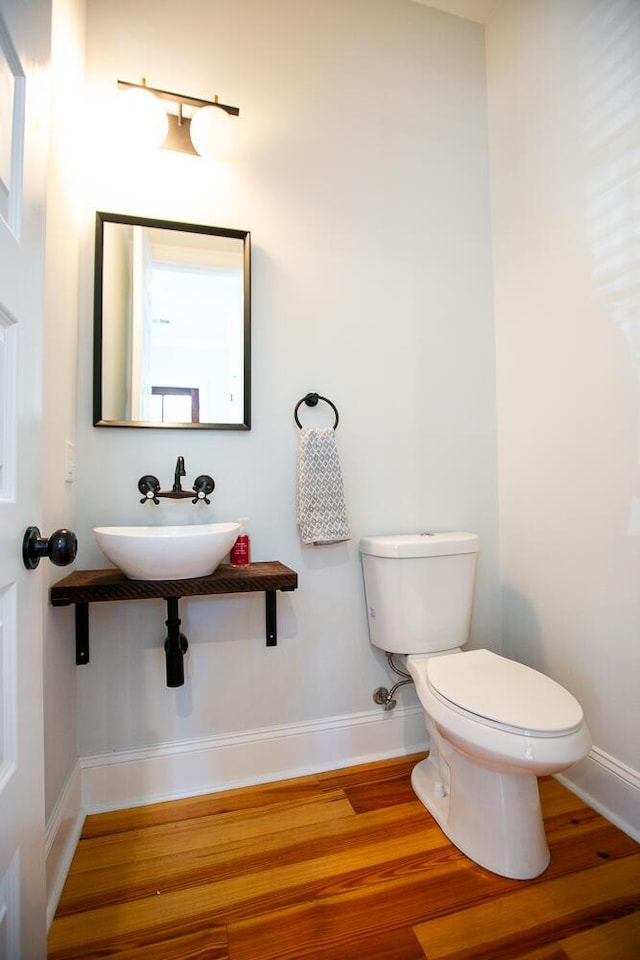 bathroom with toilet, sink, and hardwood / wood-style floors