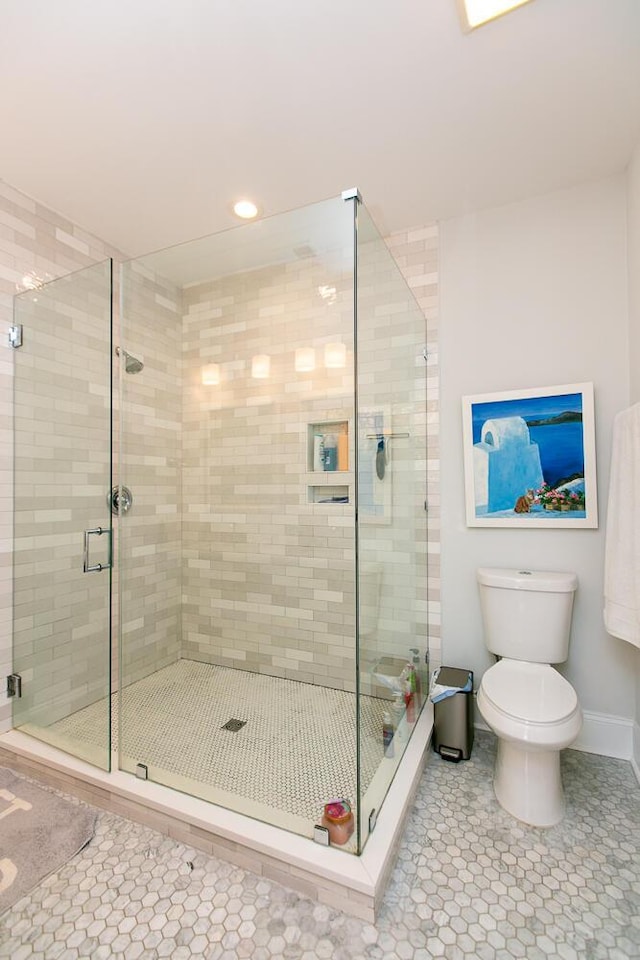 bathroom featuring toilet, tile patterned floors, and a shower with shower door