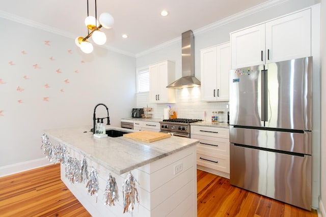 kitchen with sink, appliances with stainless steel finishes, a kitchen island with sink, white cabinetry, and wall chimney exhaust hood