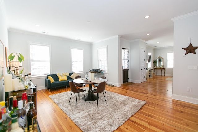 dining area with ornamental molding and light hardwood / wood-style flooring