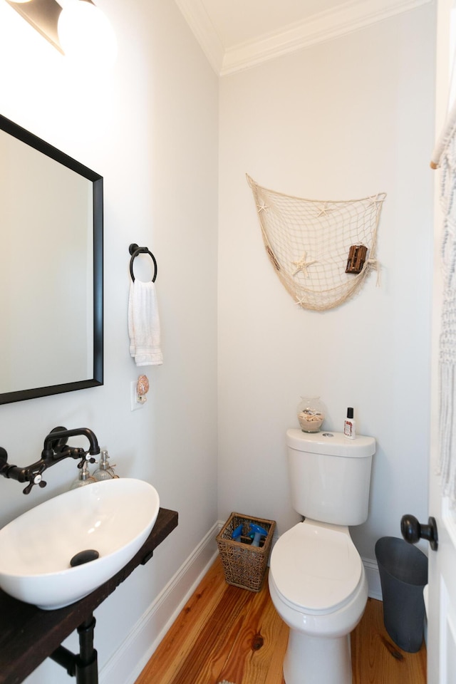 bathroom with crown molding, wood-type flooring, toilet, and sink