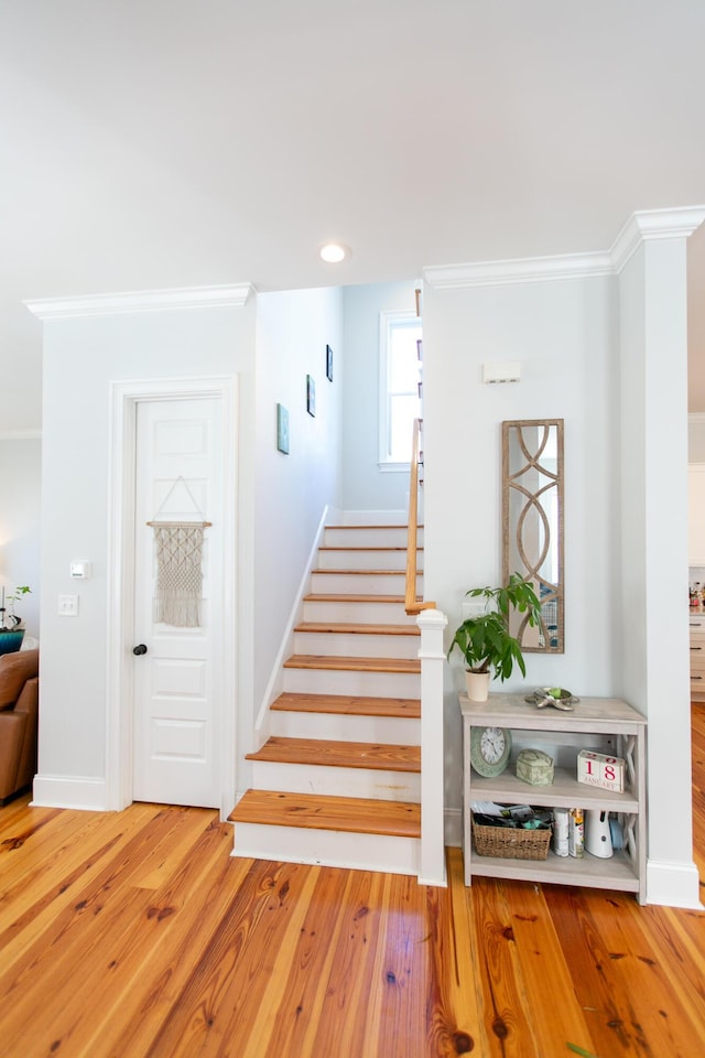 staircase with crown molding and wood-type flooring