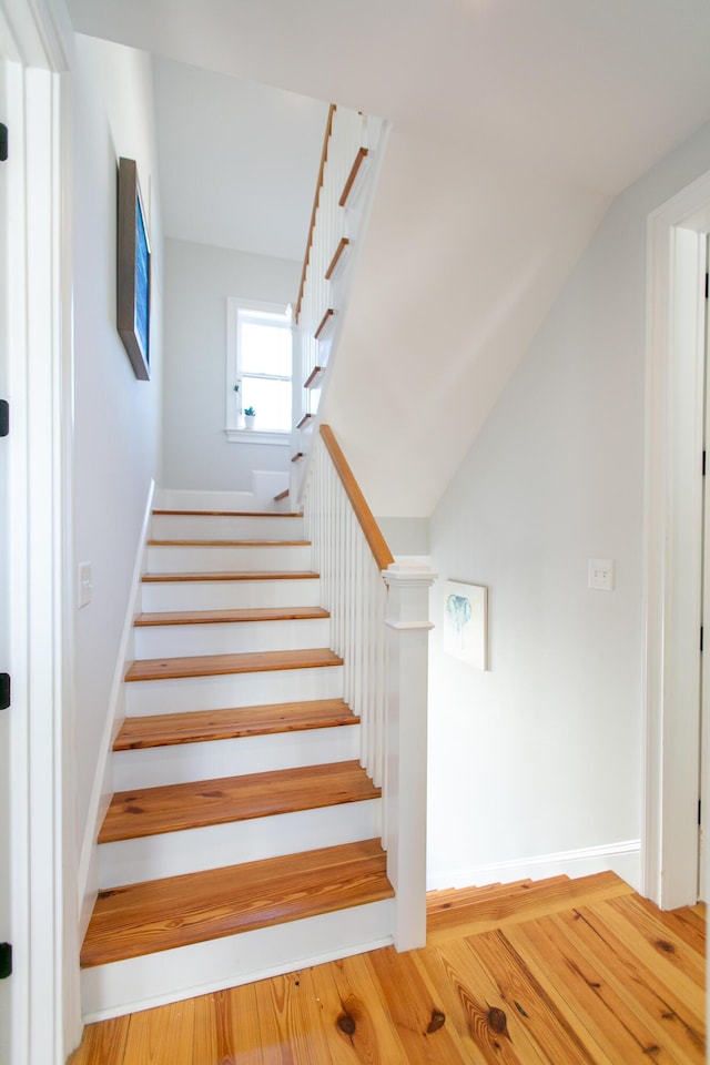 stairs with vaulted ceiling and hardwood / wood-style floors