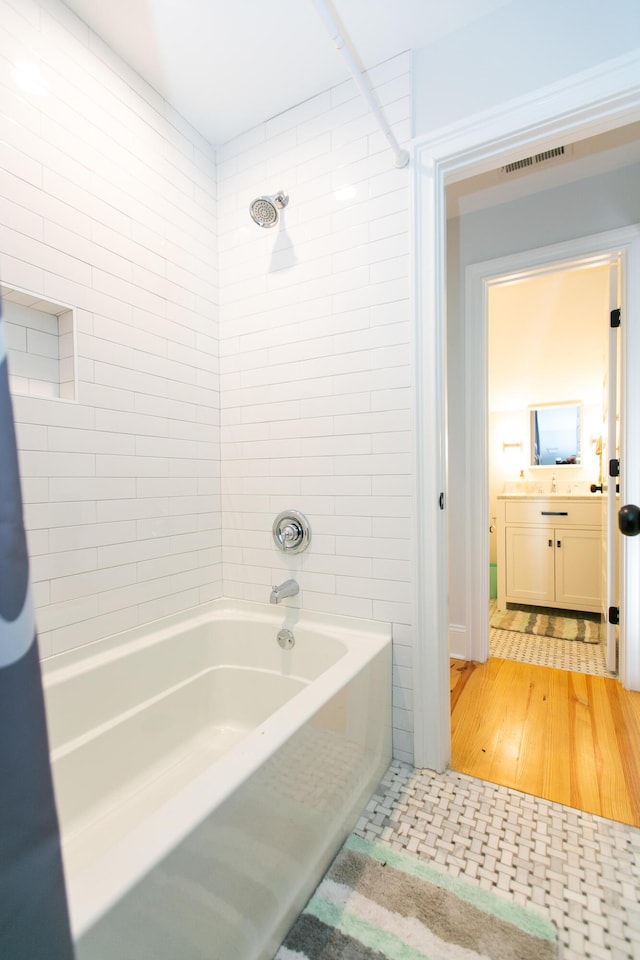 bathroom featuring vanity and tiled shower / bath