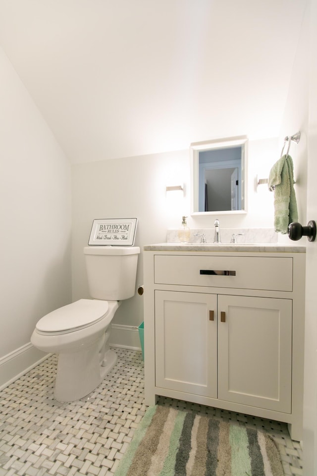 bathroom with lofted ceiling, vanity, toilet, and tile patterned flooring