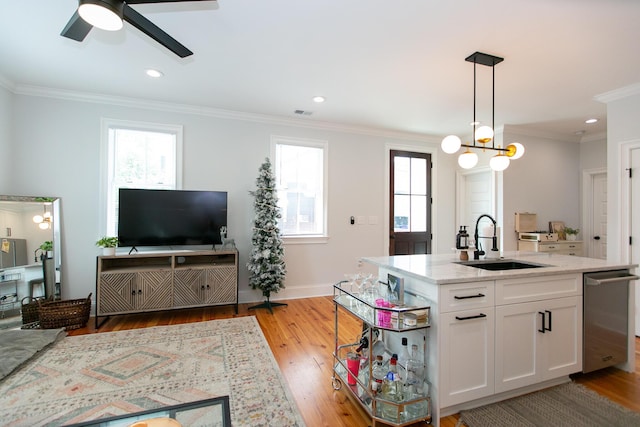 kitchen featuring sink, white cabinetry, light stone counters, decorative light fixtures, and light wood-type flooring