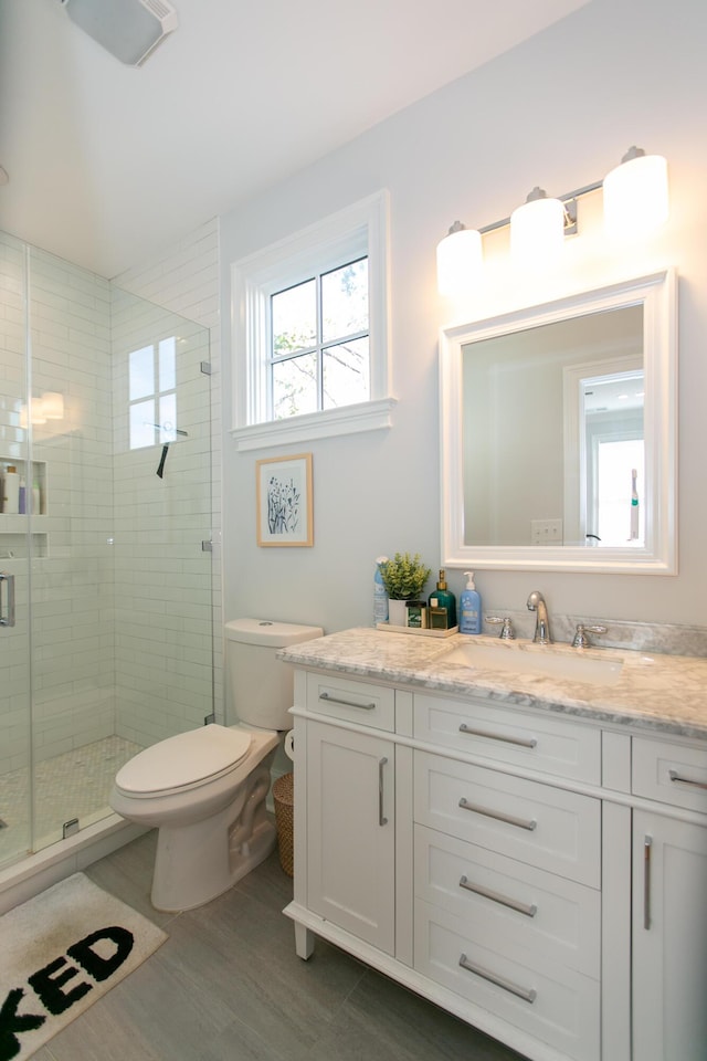 bathroom with a shower with door, vanity, hardwood / wood-style floors, and toilet