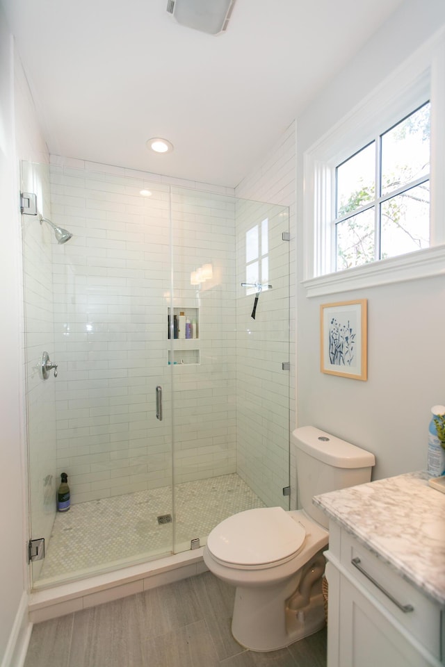 bathroom with vanity, toilet, and a shower with shower door