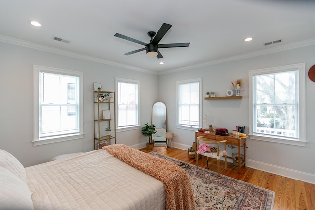 bedroom featuring multiple windows, crown molding, hardwood / wood-style floors, and ceiling fan