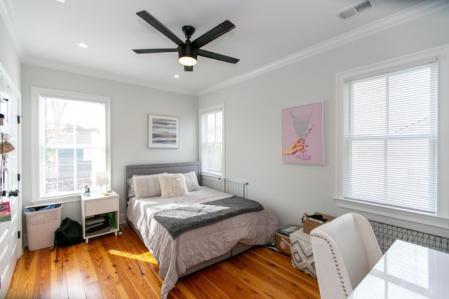 bedroom with ornamental molding, ceiling fan, and light hardwood / wood-style floors