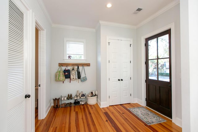 entrance foyer featuring ornamental molding, a wealth of natural light, and light wood-type flooring