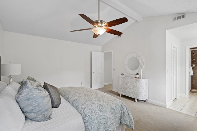 bedroom featuring ensuite bathroom, a textured ceiling, light colored carpet, ceiling fan, and lofted ceiling with beams