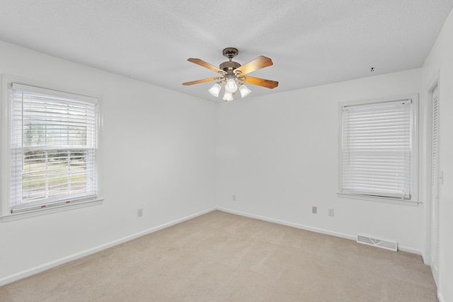 carpeted spare room featuring ceiling fan and a textured ceiling