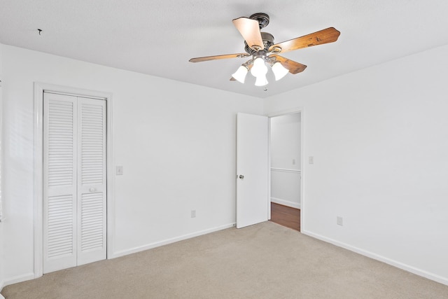 unfurnished bedroom featuring a closet, light colored carpet, and ceiling fan