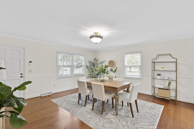 dining space with a healthy amount of sunlight, dark hardwood / wood-style flooring, and ornamental molding