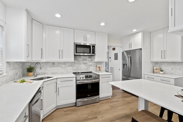 kitchen featuring light wood-type flooring, stainless steel appliances, white cabinetry, and sink