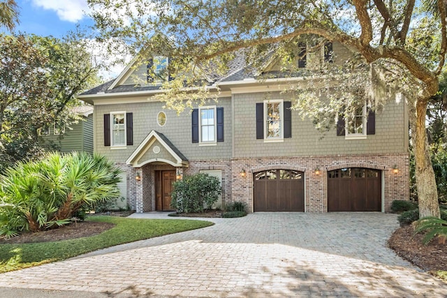 view of front of house featuring brick siding, decorative driveway, and an attached garage