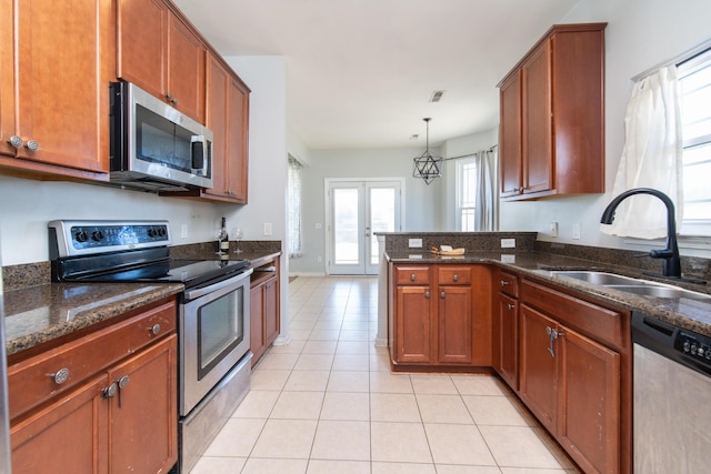 kitchen featuring pendant lighting, appliances with stainless steel finishes, sink, and dark stone countertops