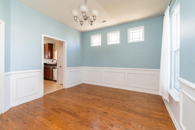 unfurnished room featuring an inviting chandelier, sink, and light hardwood / wood-style floors