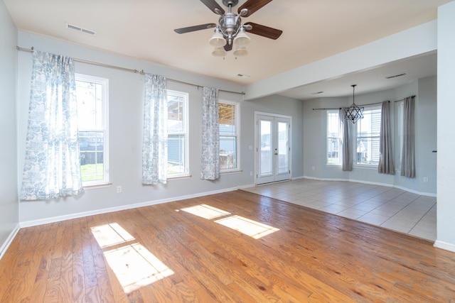 unfurnished room featuring wood-type flooring, ceiling fan with notable chandelier, and french doors