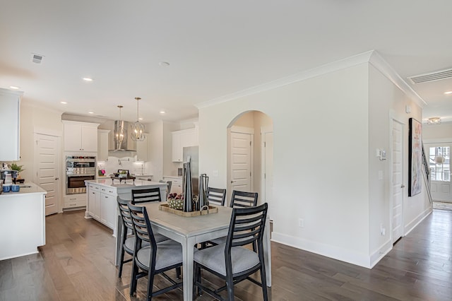 dining area with arched walkways, visible vents, baseboards, ornamental molding, and dark wood-style floors