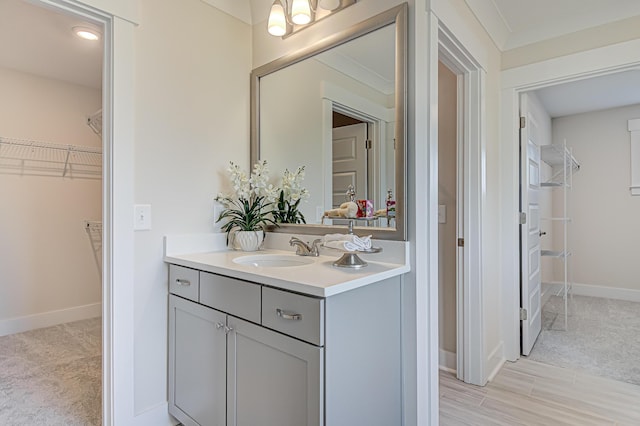 bathroom with vanity, baseboards, and a spacious closet