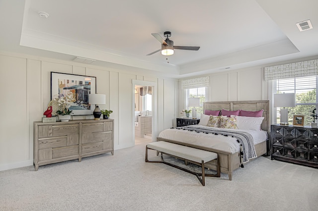 bedroom featuring visible vents, a raised ceiling, carpet flooring, and a decorative wall