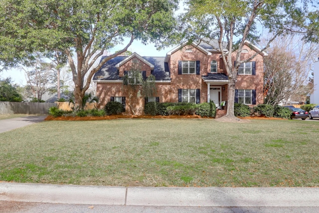 traditional-style house featuring brick siding, fence, and a front lawn