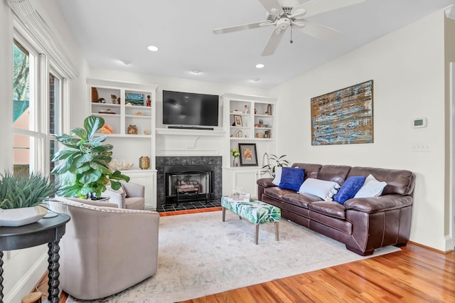 living area with recessed lighting, a fireplace, wood finished floors, and built in features