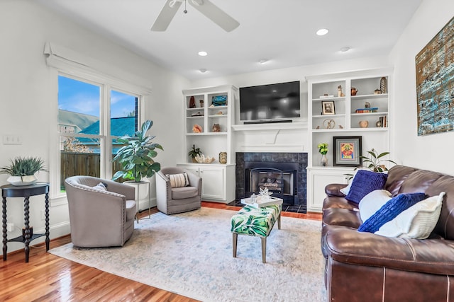 living area with a fireplace, wood finished floors, a ceiling fan, and recessed lighting