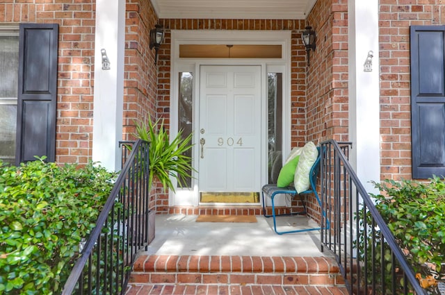 entrance to property with covered porch and brick siding