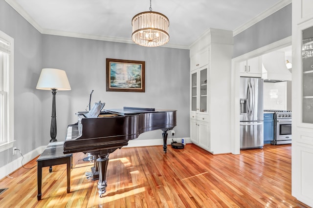 sitting room with light wood-style floors, baseboards, a chandelier, and crown molding