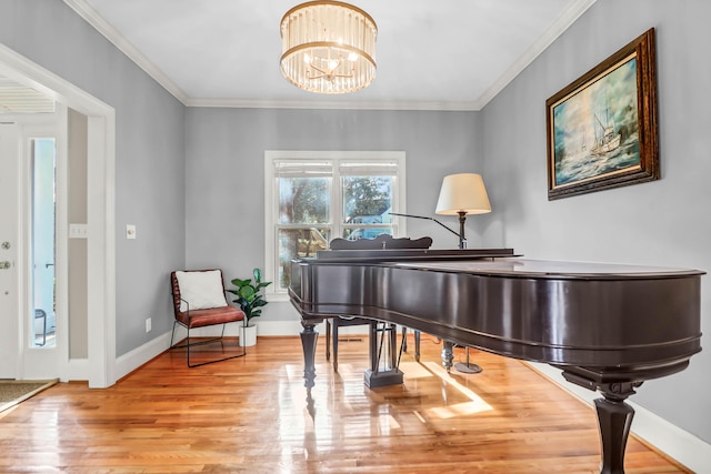 living area with a chandelier, crown molding, baseboards, and wood finished floors